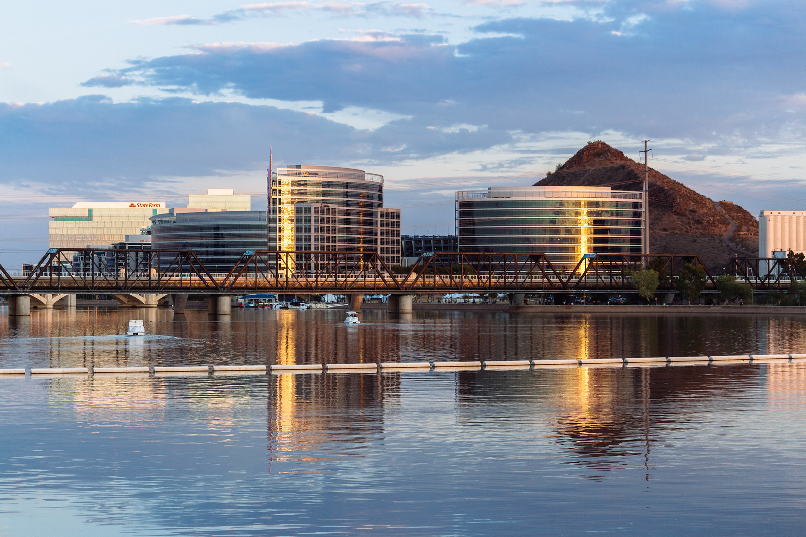 Photo of Tempe Town Lake at sunset facing Tempe Butte. A railroad track is visible over the lake.